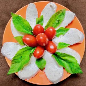 Selbst gemachter veganer Mozzarella in Rohkostqualität mit frischen Gartentomaten und Giersch