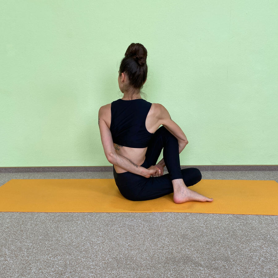 Yoga-Asanas: Fanny zeigt Ardha Matsyendrasana den gebundenen Drehsitz von hinten
