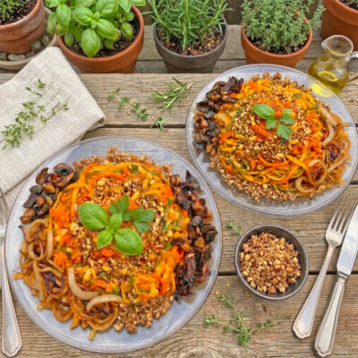 vegane Low Carb Bolognese mit Nusshack, gedörrten marinierten Pilzen und Zwiebeln plus Gemüsenudeln auf 2 Tellern angerichtet