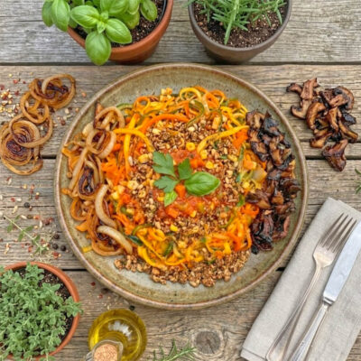 vegane Low Carb Bolognese mit Nusshack, gedörrten marinierten Pilzen und Zwiebeln plus Gemüsenudeln auf Teller angerichtet