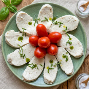 selbstgemachter veganer Mozzarella mit frischen Garten-Tomaten und Kräutern